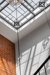 Intricately designed metal plates, inspired by the essence of home, cast ever-changing shadows along the stairwell, tracing the passage of time in delicate patterns.