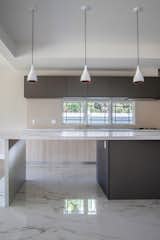 The kitchen island, topped with a sleek marble finish, anchors the open space.

Above, pendant lights offer both function and minimalist elegance, enhancing the clean lines and modern design.