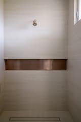 The master shower in our Arcadia features a warm color palette and matte texture.

A horizontal bronze band juxtaposes the tall space.

A gentle natural light falls in from the high window.