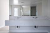 A floating vanity with elegant white marble creates a clean, linear element, while wall-mounted sinks in brushed nickel add a sleek finish.