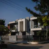 Contemporary facade of a modern house with geometric forms, large balconies, and a gated entrance.
