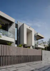 A monolithic concrete volume anchored by a bold cantilever, framed by vertical louvers and planar symmetry.