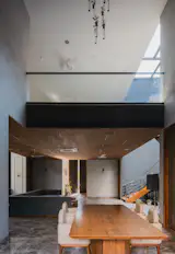 Open-plan dining and living area with wood accents, modern lighting, and a visible stairway leading to an upper level.