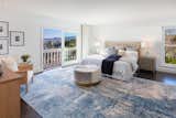 AFTER: removed the wood wall, lovely blue, white and beige color pallette accents the beautiful views from the windows and deck and makes the space seems larger, brighter and gender neutral. Large blue rug covers the dark floors