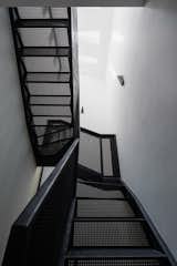The iron mesh staircase filters natural light throughout the interior, enhancing brightness and openness.