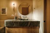Powder bathroom featuring a fusion marble with a curved corner and integrated sink. Trueing wall sconce, custom mirror and polished nickel fixtures.