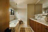 Primary bathroom with stained oak cabinets, honed money marble and antique brass fixtures.