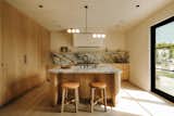 Kitchen features a curved island, plaster walls and hood covering. All appliances besides the stove are built in to the cabinets. The stove is Monogram, faucet is Newport brass. 