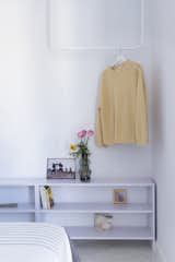 Pale purple shelves barely contrast the white walls and clothes rail.