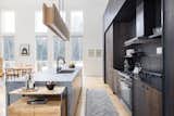 Dark wood cabinetry contrasts with the light wood flooring and monolithic quartz island.