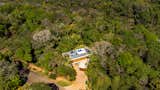 Aerial view of Deltrap House, located amidst the native forest of Serra do Japi. The modern architecture blends into the surroundings with clean volumes and a layout that respects the natural topography.
