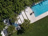An aerial view of a serene poolside retreat, where geometric pathways and lush greenery create a harmonious outdoor oasis.