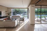 This space beautifully integrates modern architecture with nature, thanks to its floor-to-ceiling glass doors that open up to a lush outdoor area with a pool. 
