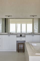 A tranquil primary bathroom featuring a tadelakt plaster tub and a double vanity that reflects the soft elegance of the space. The natural light enhances the tadelakt plaster walls, while minimalist chrome fixtures and a vintage wooden stool add warmth and character. A seamless blend of function and refinement, designed for quiet moments of retreat.