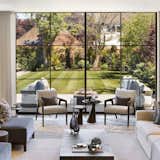 This serene living room blurs the line between indoor luxury and outdoor beauty, featuring floor-to-ceiling glass walls that open up to a meticulously manicured garden. The space is a study in elegance and tranquility, where neutral tones and soft furnishings enhance the sense of calm.

Modern lounge chairs and minimalist side tables invite conversation, while sculptural vases and clean-lined décor add a curated touch. Natural light floods the room, creating an airy, open atmosphere—perfect for quiet mornings or stylish entertaining. A true celebration of contemporary living in harmony with nature.

