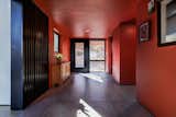 A rich brick-red paint on the walls and ceiling of the hyphen, which connects the existing and new volumes of the home, continues throughout the entire house.