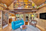 The open-plan living and dining area showcases sculpted ironwork, custom built-ins, and forest views—topped with a cozy loft above the main gathering space.