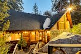 Twilight view of the front entry, where stonework, snow-dusted shingles, and golden interior light create a warm mountain welcome.