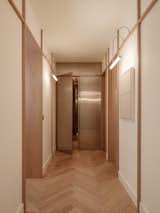 Panelled corridor featuring bespoke wall lights and a stainless steel wall revealing the red travertine bathroom