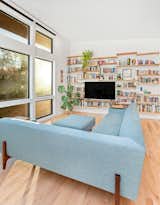 Living room with floor-to-ceiling windows, locally sourced wood bookshelf designed and crafted by clients