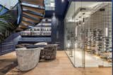 The thermally regulated wine room, housing 684 bottles, is discreetly accessed via two hidden doors, one of which composed of a striking six hundred pound slab of backlit rainbow onyx. 