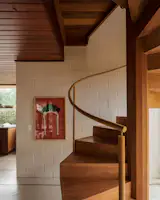 A bold yellow staircase spirals through the center of the home, offering shifting views of the garden and artwork along the way.