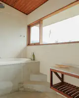 Natural light floods the bathroom, highlighting the concrete base and warm, earthy palette.