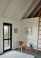 The loft was updated with an Eames Lounge Chair, Anchor Ceramics coffee table, and Colleen Guiney’s Cliff House 2, adding considered pieces that feel at home in the cabin.