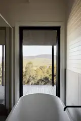 The ensuite in the parents’ retreat opens to the surrounding bush through a generous picture window. 