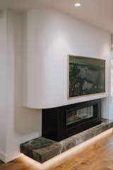 New electric fireplace with TV mounted above, curves mimics the staircase design and contrasts against the new marble plinth which elevates above the floor enhanced with LED strip lighting. 
