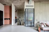 The transition between interior and exterior spaces features exposed concrete elements, black metal detailing, and an industrial aesthetic softened by timber accents. The HVAC duct is intentionally exposed as part of the design language, demonstrating the architect's approach to integrating technical elements.