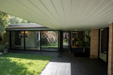 A dramatic 27-foot glass curtain wall replaced the rear hallway, converting it into a gallery-style corridor that floods the home with natural light and creates a striking visual connection to the backyard.
