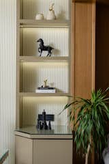 Built-in shelves house curated sculptures and objects, providing quiet moments of visual interest. Natural wood accents and monochromatic accessories add warmth and contrast to the otherwise restrained palette.