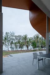 By the beach amidst coconut trees, a house is a framing device that shelters.