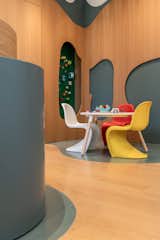 Close up of play area with sculptural chairs and built in green LEGO wall.Organic forms tactile materials and playful seating define the childrens corner along the forest mural 