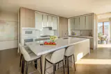 The gourmet chef's kitchen includes stained ash wood cabinetry with fluted glass upper cabinets and polished Bianco ice marble countertops and backsplash. 