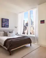 Celestial Blue by Chellis Baird adds textural interest above the bed. The intimate scale of waiting, 9, Negril, 2024 by Alexandria Tarvier is in direct contrast to the dramatic Manhattan views through the bedroom's oversized windows. 
