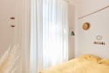 A light-filled bedroom featuring a curated wall of artworks and personal objects that evoke cherished memories.