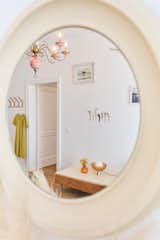 An 80s-era mirror reflects the bedroom’s oversized floral chandelier and curated wall of artworks.

