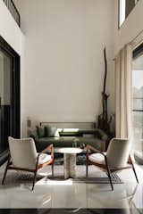 Double height Drawing Room-An elegant conversation zone where sculptural furniture meets soft light. The palette of muted neutrals is punctuated by a rich green daybed and accents of wood and stone.