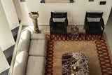 This living room features a plush neutral sofa, bold black leather chairs, and a striking marble coffee table atop a patterned rug, blending contemporary comfort with timeless sophistication.