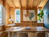 Inside, exposed wood framing and built-in shelving create a warm, textured backdrop for the meeting room. Simple furnishings and natural light reinforce the project’s commitment to raw materials and straightforward construction.
