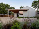 The deep front porch extends the studio’s small footprint, creating a shaded threshold between interior and garden. A raised planter integrates soft landscaping with the building’s corrugated Galvalume exterior.
