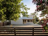 From the neighbor’s yard, the studio’s modest profile and simple gable form blend into the residential fabric. The porch and gravel yard create a soft, open edge that reinforces the project’s connection to its Montopolis context.