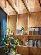 Built-in 2x10 shelving houses books, personal mementos, and plants, softening the raw structure and revealing how the space balances professional function with everyday warmth.