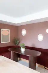 Tucked into a sunlit corner off the kitchen, the custom banquette pairs maroon velvet upholstery with a cozy, built-in feel. A thatched-texture wallpaper wraps the back wall, adding depth and warmth, while sculptural RBW sconces in organic forms create a soft, layered glow. Overlooking both the kitchen and the river, it’s a daily gathering spot for slow breakfasts and quiet moments.